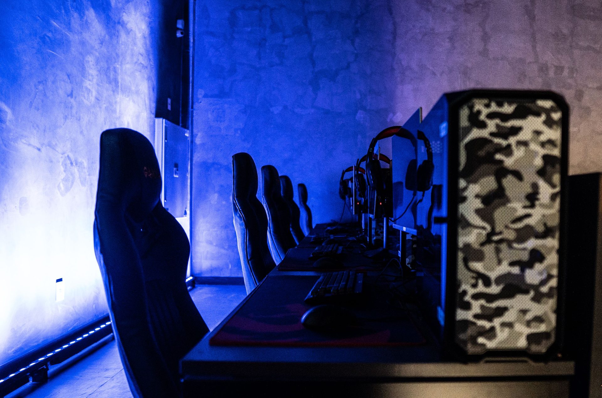 Players at neon-trimmed PIXELPET stations wearing headsets during a busy session